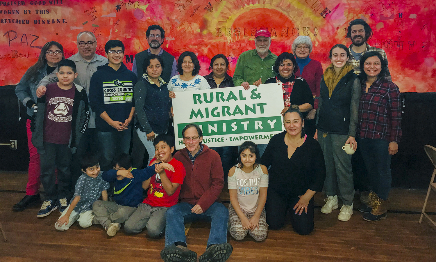 group photo with sign that says "Rural and Migrant Ministries"