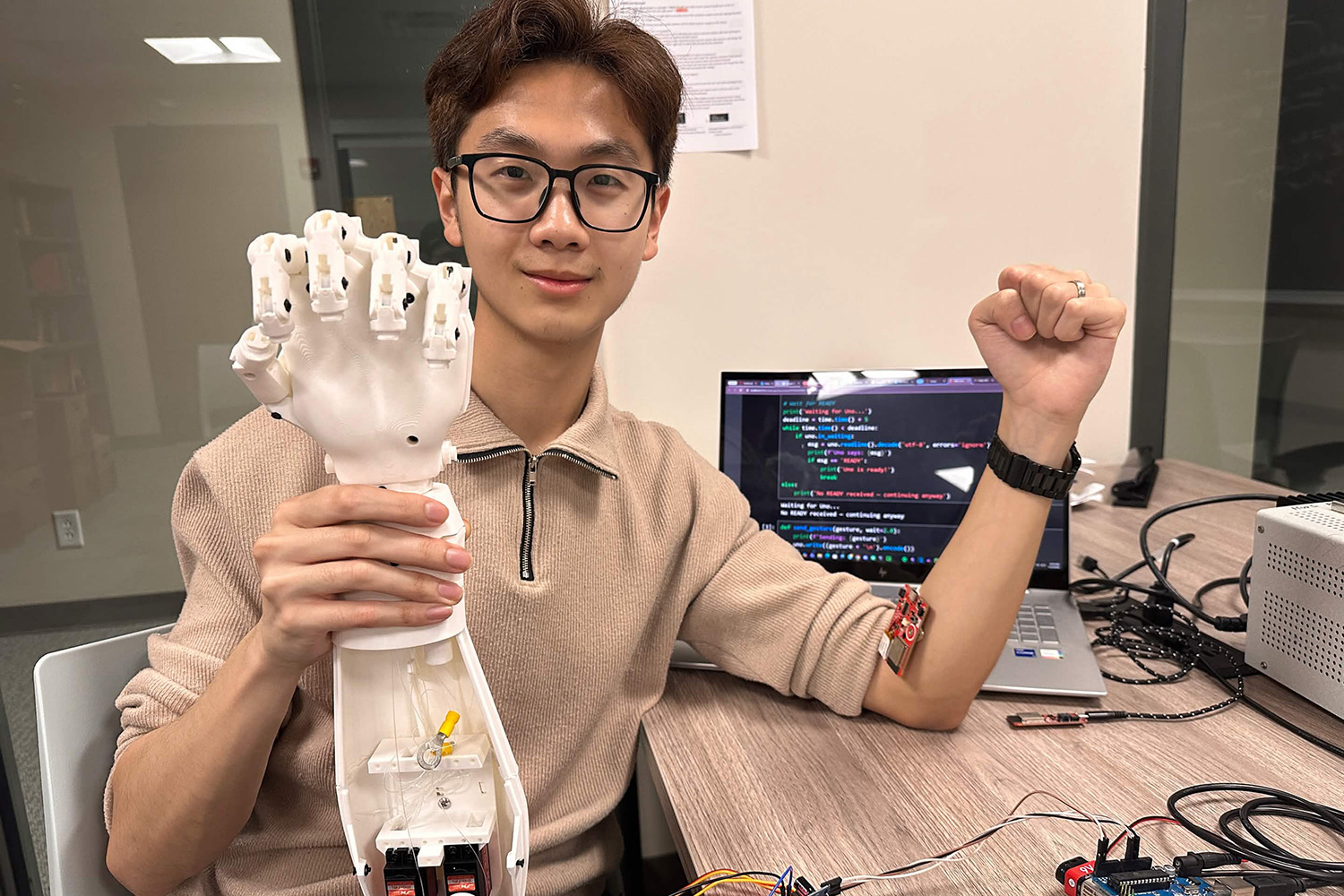 Randy Hong '26 poses with the mechanical arm he designed and programmed. 