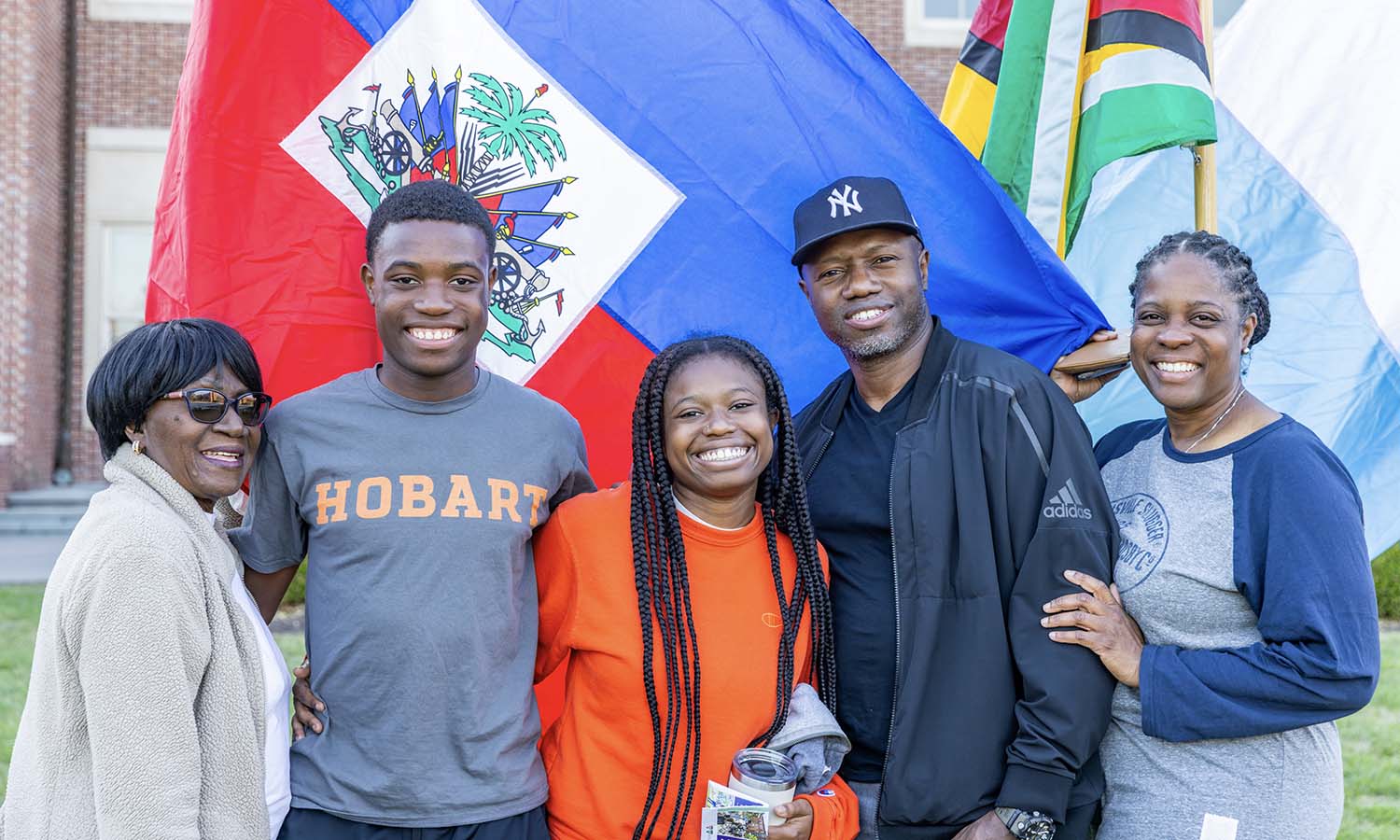 Nigel Presume ’29, from Mahopac, N.Y., and family gather for a photo in front of the flag of Haiti.  