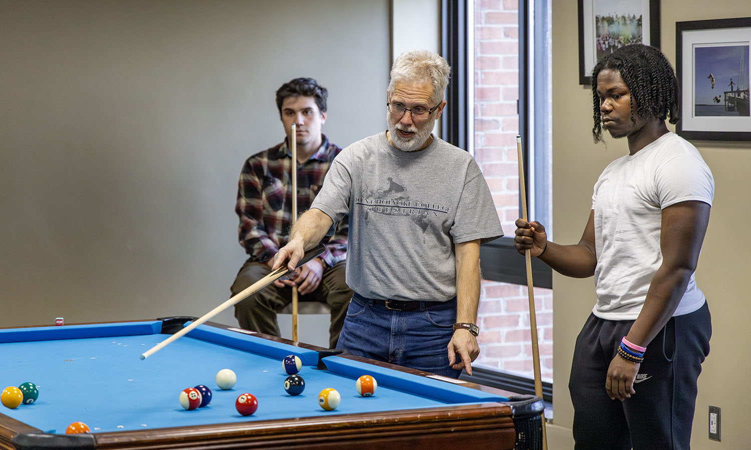 Professor of Philosophy Eric Barnes explains various shot options to Johnnie Clay ’28 during “Billiards,” a no-credit course offered to the HWS community through the Recreation Department.  Barnes explains that the best shot here seems to be a three ball combination, shot firm with a bit of draw.  