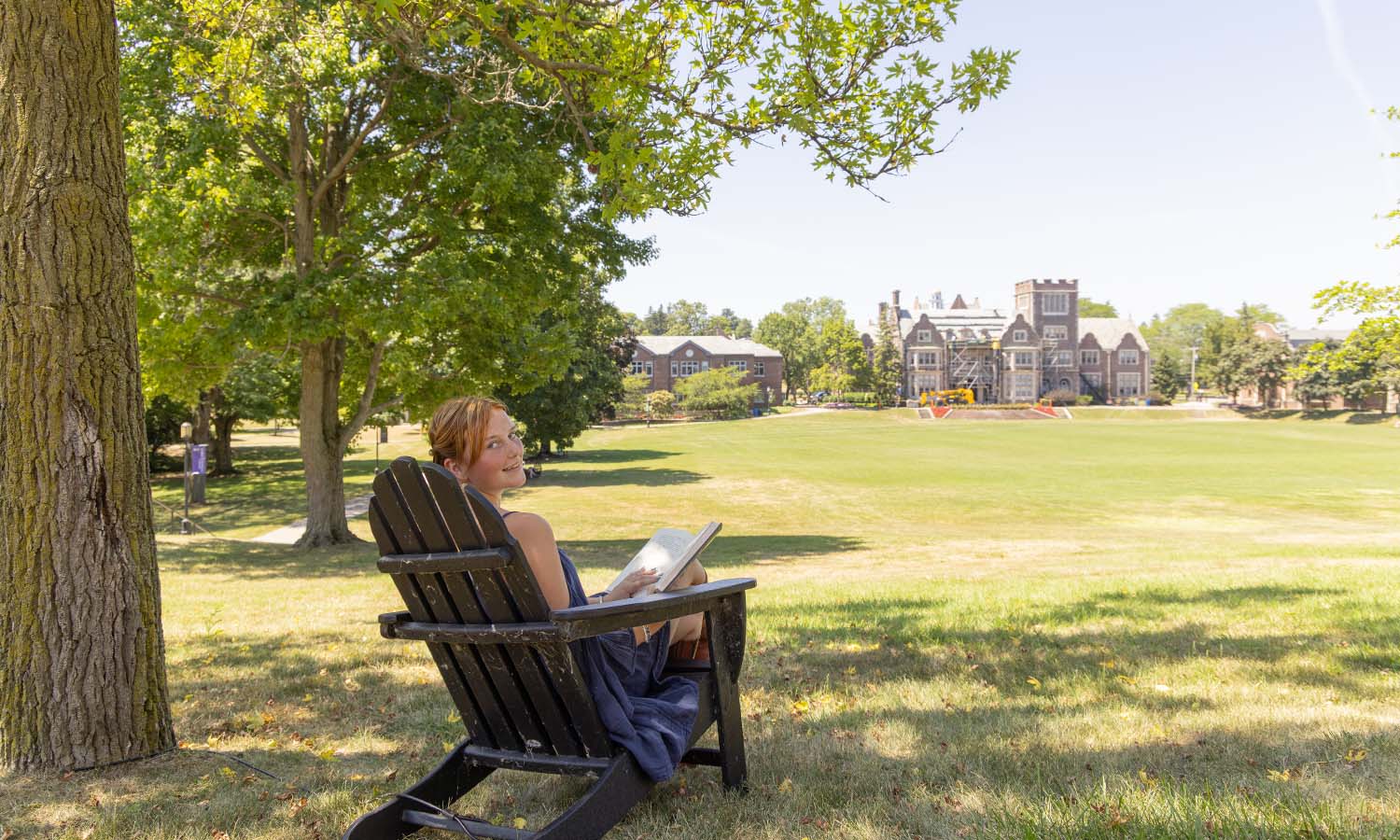 Maggie Mahoney ’26 reads in the Adirondack chair behind Trinity Hall, where she can overlook the Quad while relaxing or studying. 