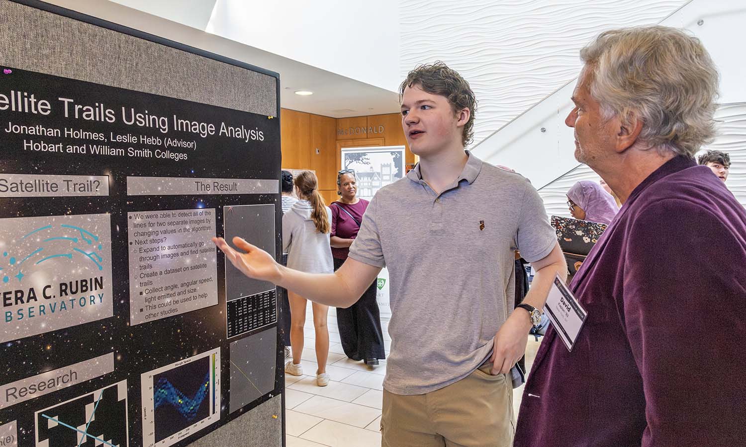 Jonathan Holmes ‘28 explains his summer research project with Professor of Physics Leslie Hebb to David Kaplan ’83. 