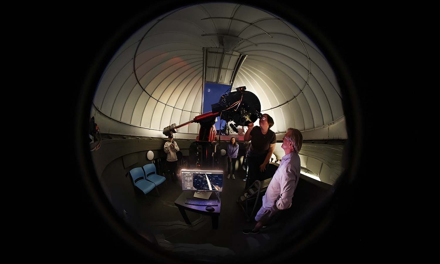 Associate Professor of Geoscience David Kendrick helps students and their families to view the moon at the Richard S. Perkin Observatory open house. 