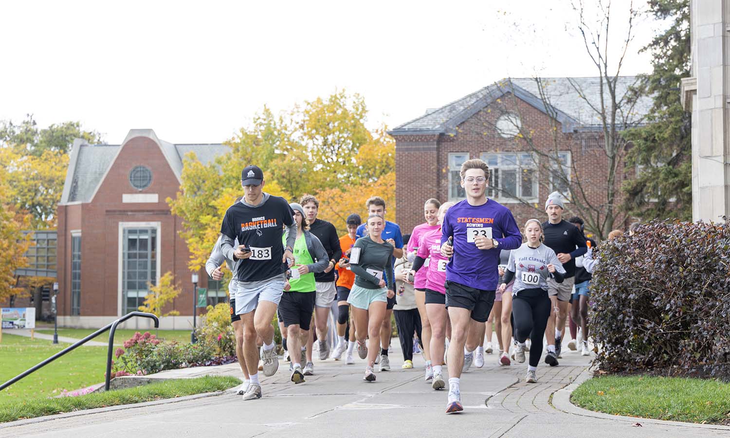 Students participating in the Run Club Charity 5K race past Coxe Hall to raise funds for Safe Harbors of the Finger Lakes. 