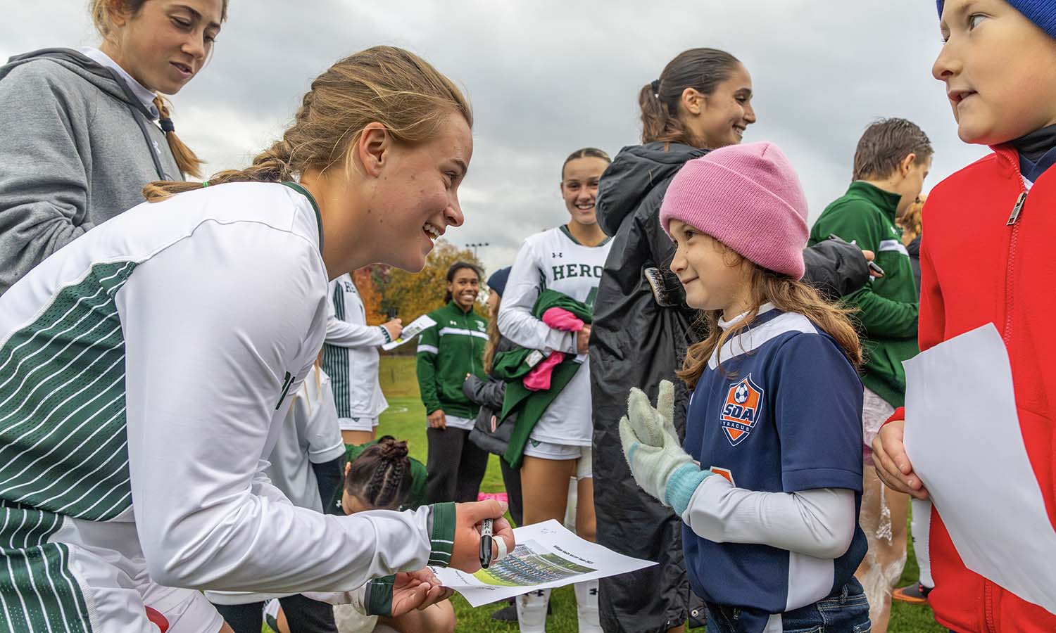 After their victory over Union, Analise Pilarski ’28 and the William Smith soccer team sign autographs for kids from the Syracuse Development Academy soccer program. 
