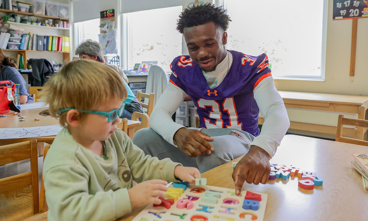 Members of the Hobart football team visit Happiness House in Geneva. Here, Sirewl Cox ’29 works on an alphabet activity with students. 