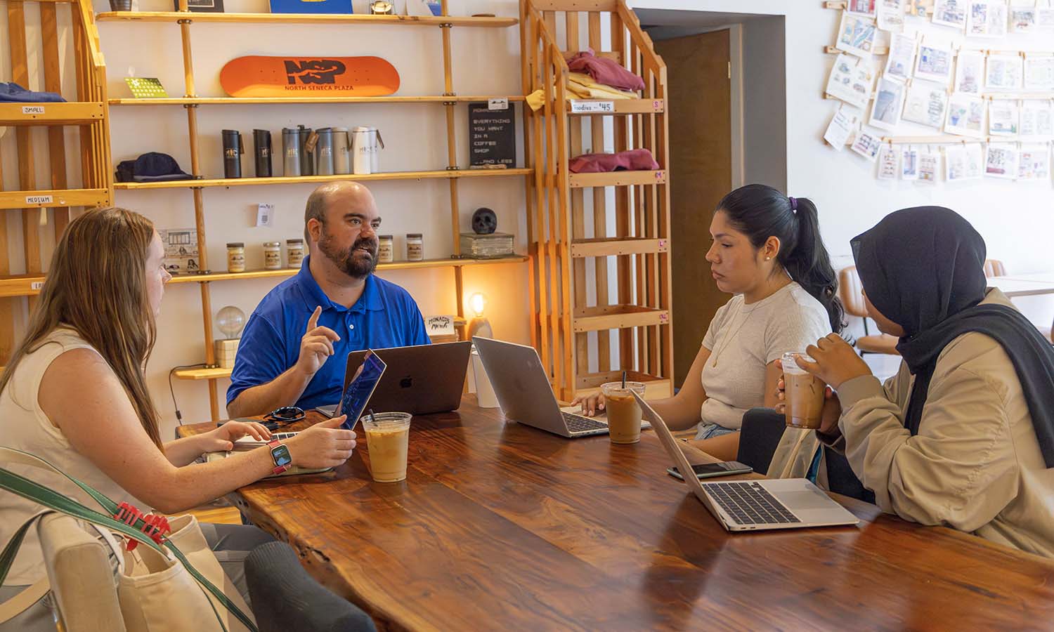 Maggie Woodruff ‘26, Hailey Galvan ‘26 and Najma Ahmad ‘26 meet with Associate Professor of Business Management and Entrepreneurship Craig Talmage to discuss the importance of neolocalism in tourism and community development. 