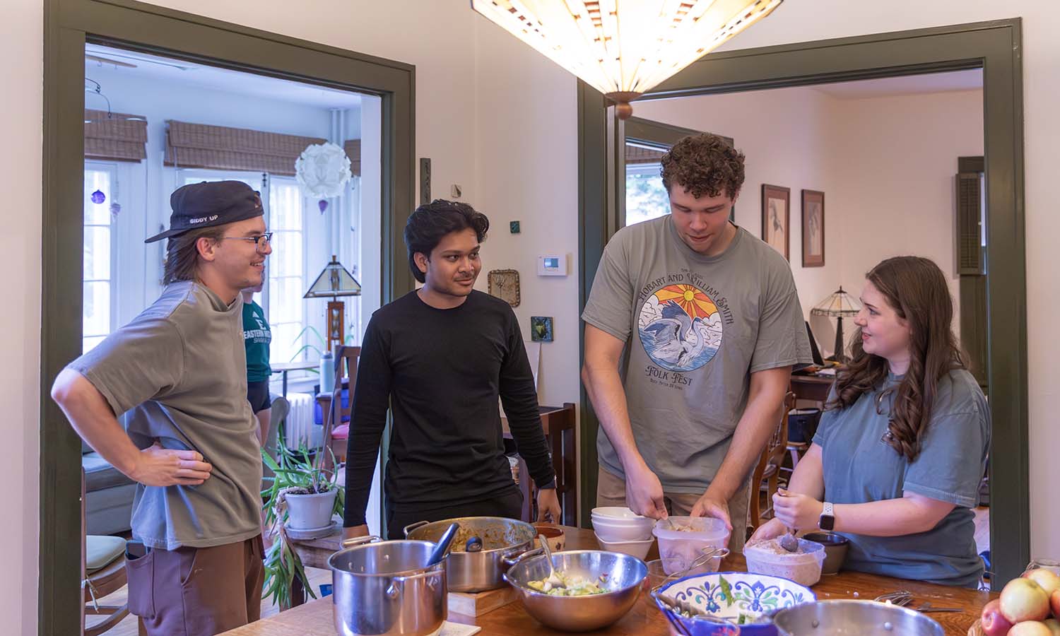 Summer research students Joel Stoneham ’26, Shaimum Alvee ’29, Mikyle Polcari ’27 and Bailey Gervais ’27 help serve dinner at the home of Professors of Geoscience Nan Crystal Arena and David Kendrick. 