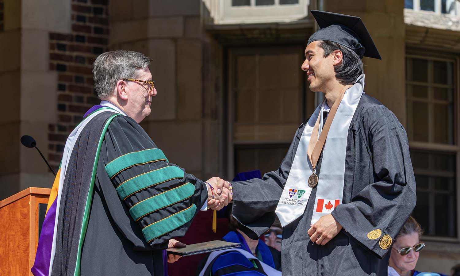 Damon Beaver '26 receives his diploma from President Mark D. Gearan. Beaver is the NCAA Division III Men's Ice Hockey Player of the Year.  