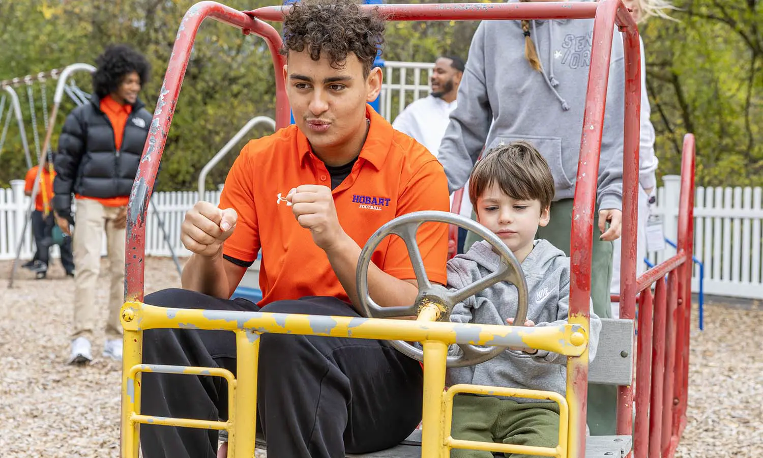 Members of the Hobart football team visit Happiness House in Geneva. Here, Braedon Serna ’28 plays on the playground with students. 