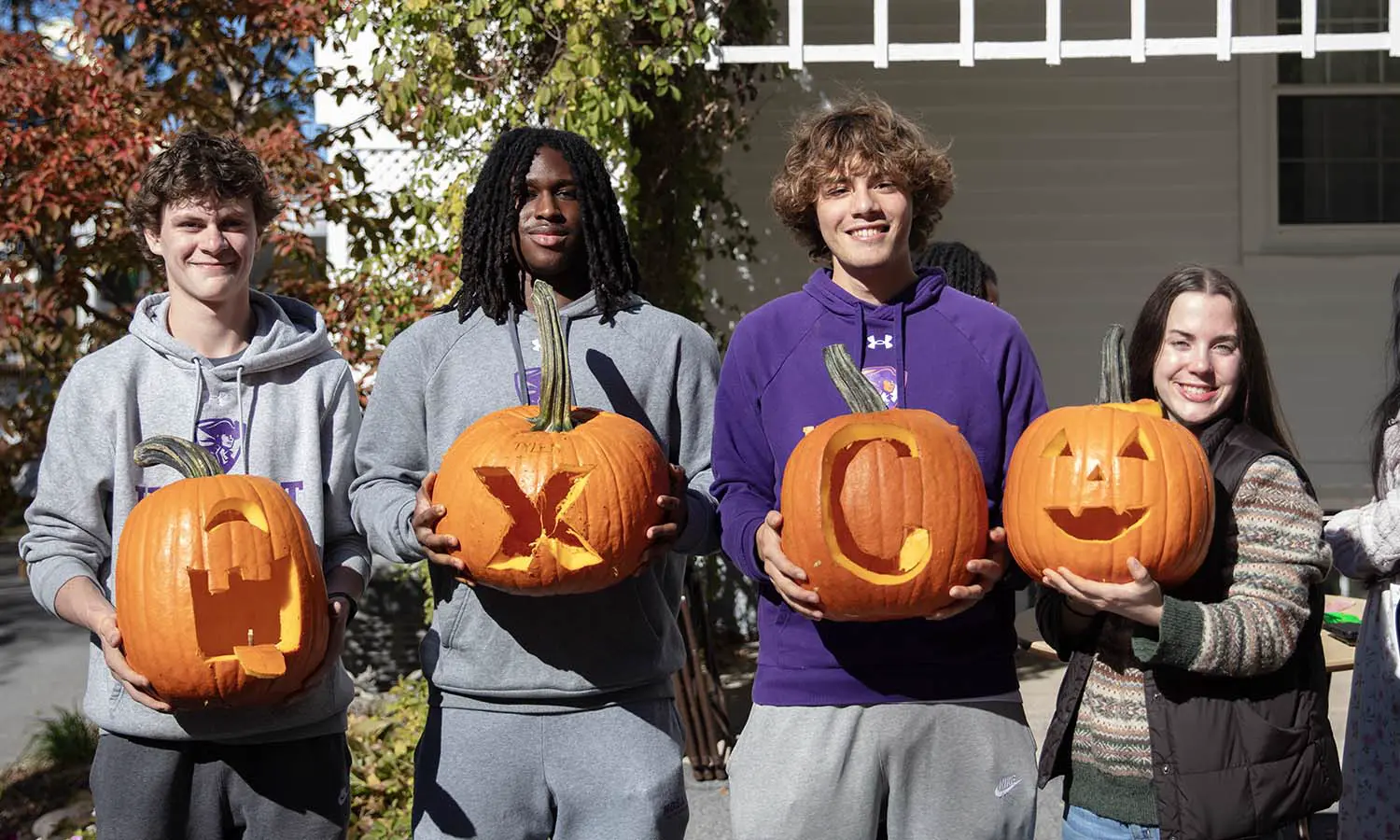 Kai Wilson '30, Chris Charles '29, Nathan Bickett '29 and Reese Wishard '29 show off their Cross Country themed pumpkins carved at President Mark D. Gearan's residence.  