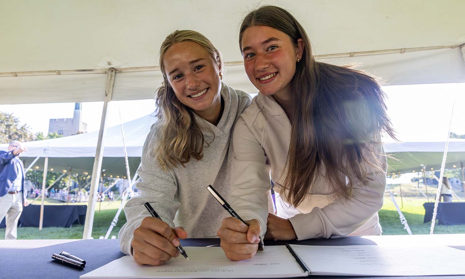 Violet Quijada ’30 and Mariana Diaz ’30 sign the matriculation book on the Quad. 