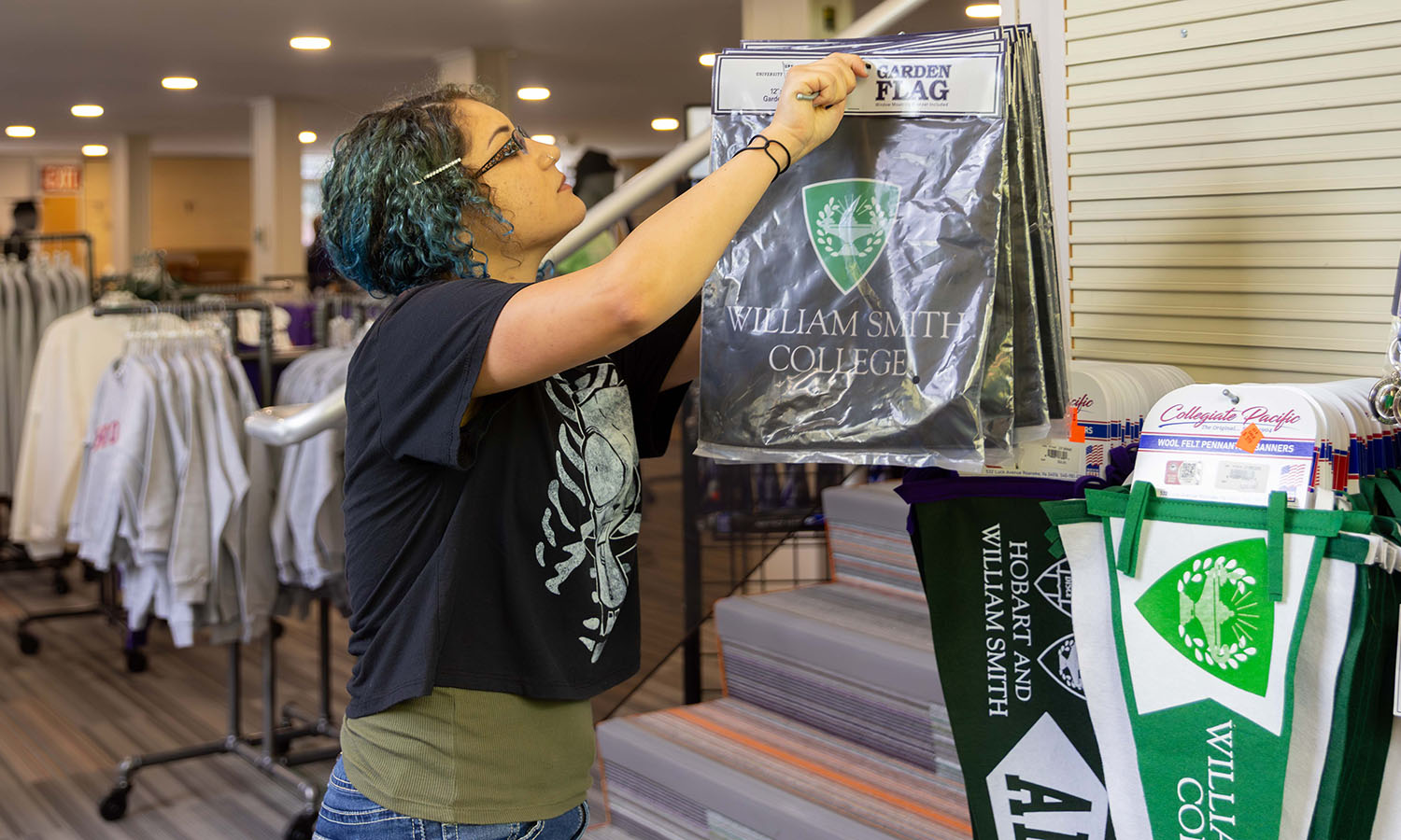 Azure Sage ’27 hangs up merchandise in the newly renovated HWS bookstore. 