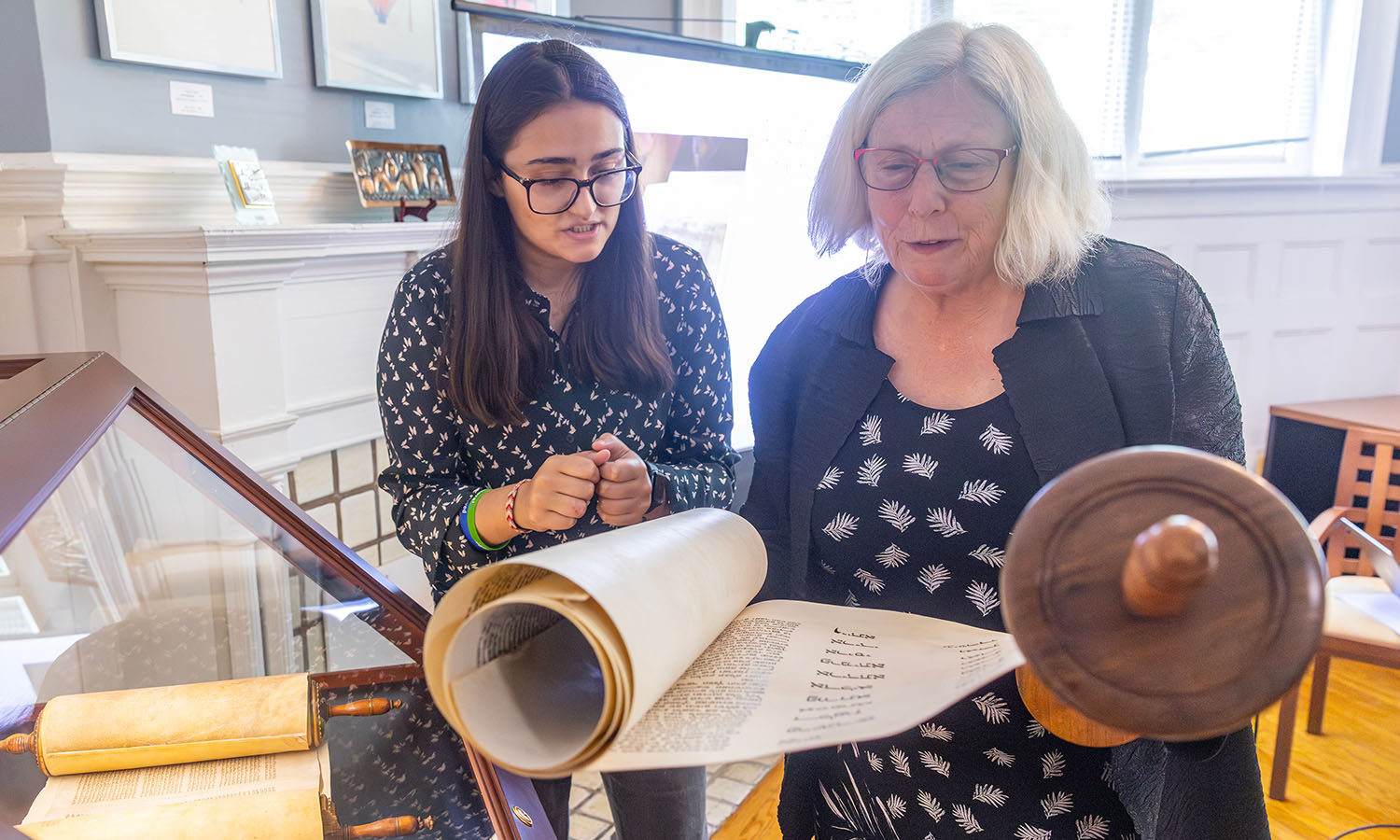 Sophia Mughal ’25 and Director of the Abbe Center for Jewish Life Rabbi Dr. Ann Landowne examine a torah during the Abbe Center Open House. Mughal uncovered the previously unknown date and location of origin of the Torah and Esther schools in HWS’ possession.  