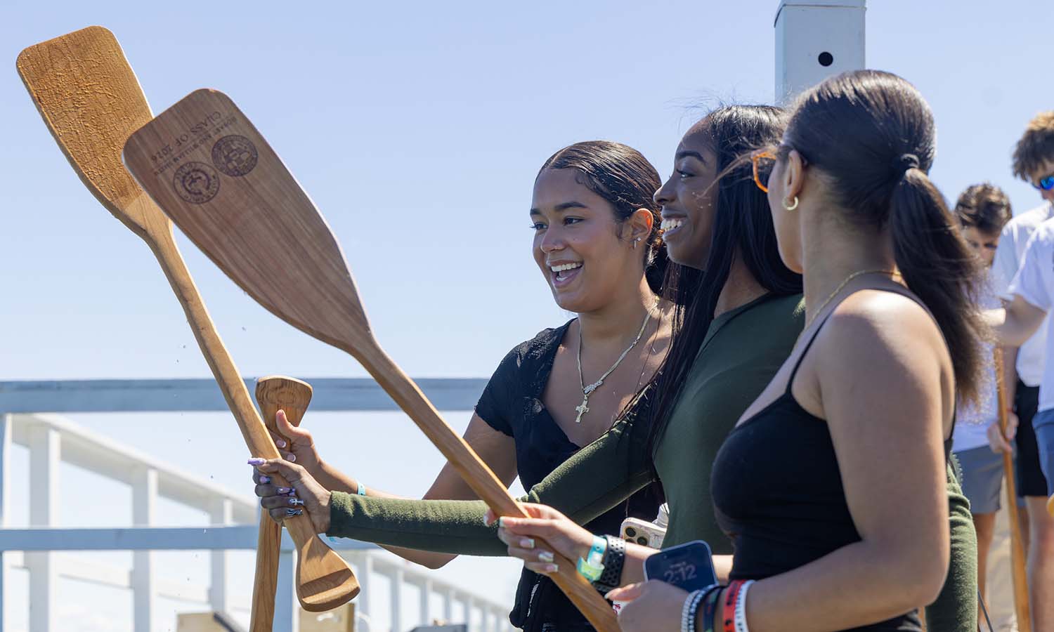 Gissel Tavarez ’26, Tamia Rollaing ’26 and Indiah Kent ’26 smile after dipping their paddles into Seneca Lake. 