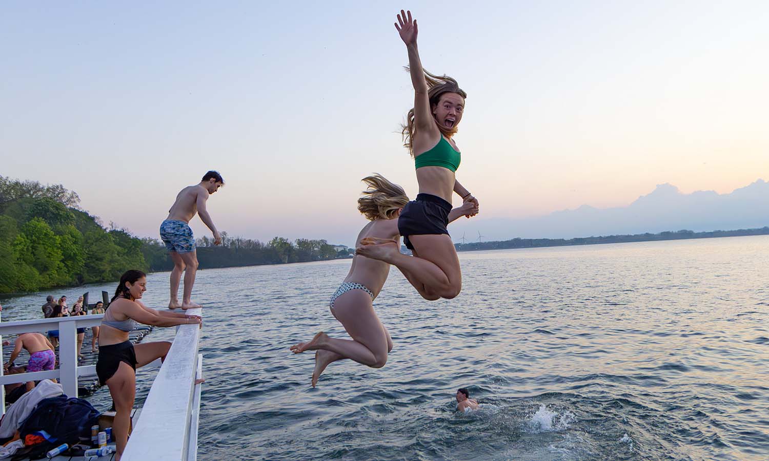 Kate Broderick ’26 and Anneliese Oetsen ‘26 jump into the water after sunrise. 