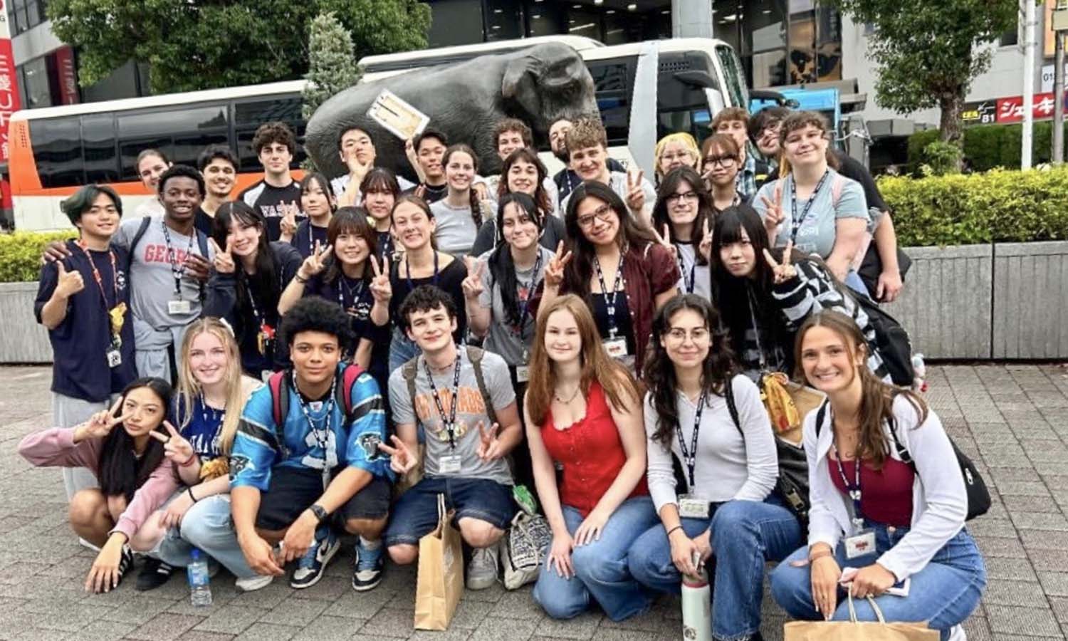 Caroline Lyddane ’28 (second from left, front row) and Roland Gardner-Olesen ’29 (sixth from left, back row) pose with fellow students at Technos International College outside Kichijoji Station. 