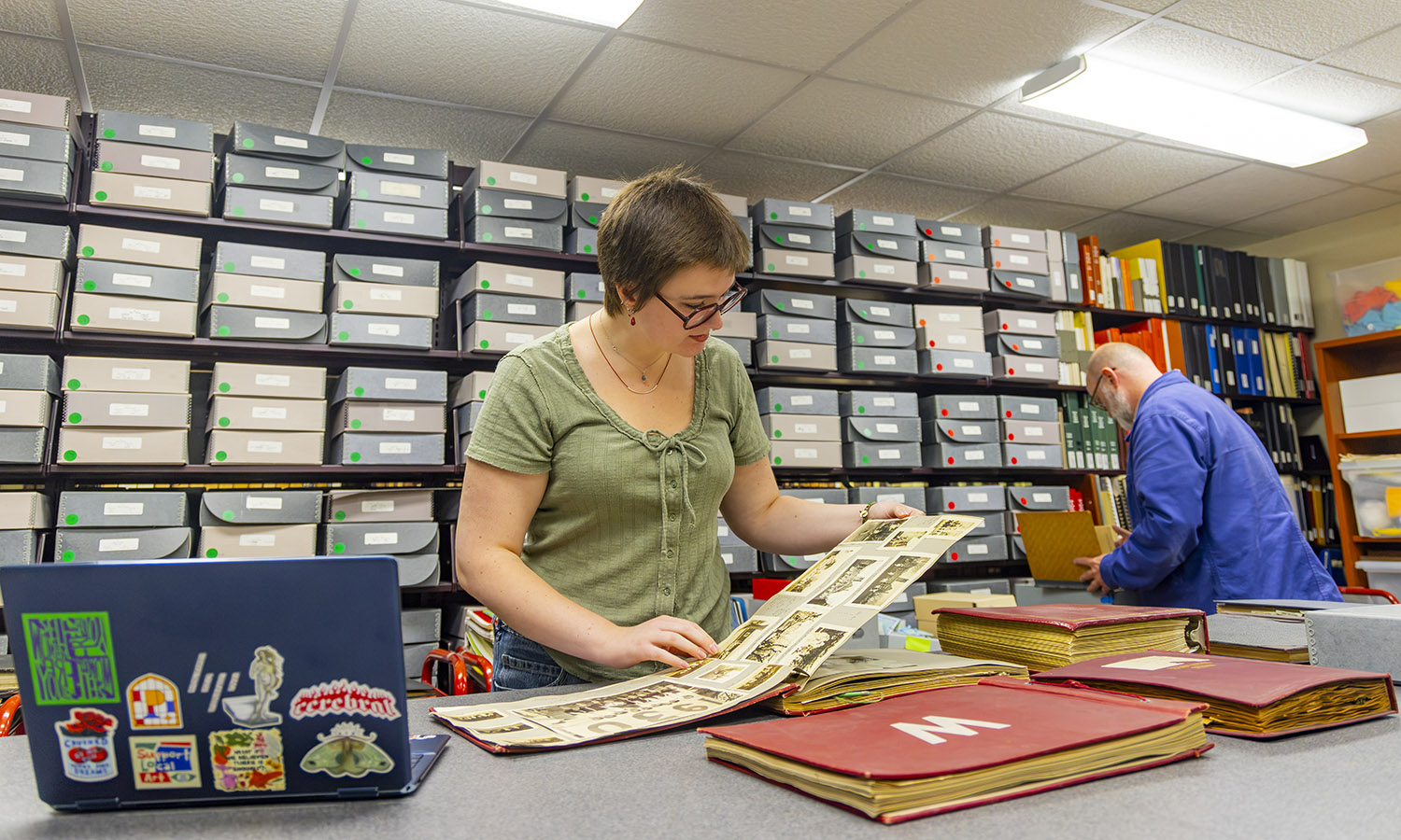 India Buff '27 reviews a scrapbook while assisting Archivist and Special Collections Librarian Brandon Moblo to process and create finding aids for Wells College archival collections. 
