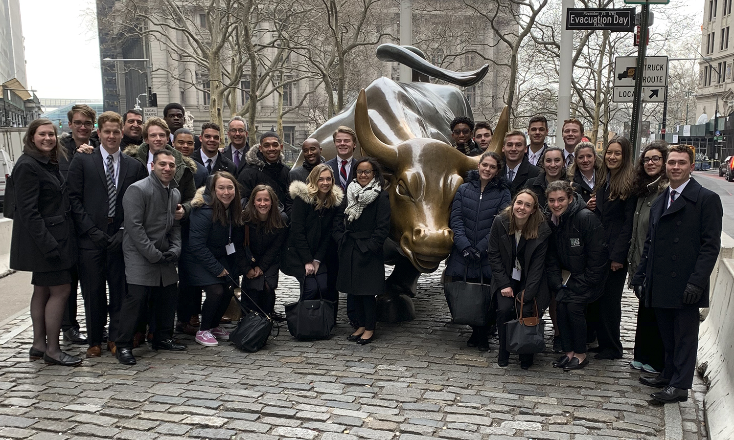 Students gather around the bull statue on Wall Street