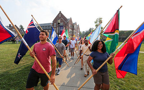 International students carry their country's flag during a Convocation ceremony.