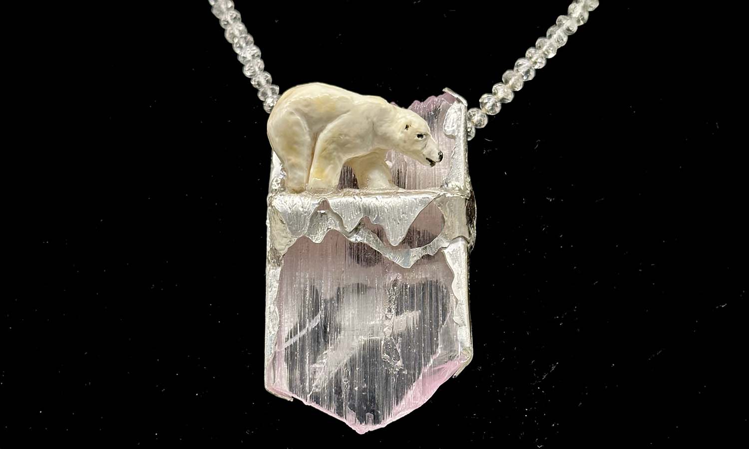 "Polar Escape" is carved from Warthog tusk and mounted on a Kunzite crystal, in silver. 