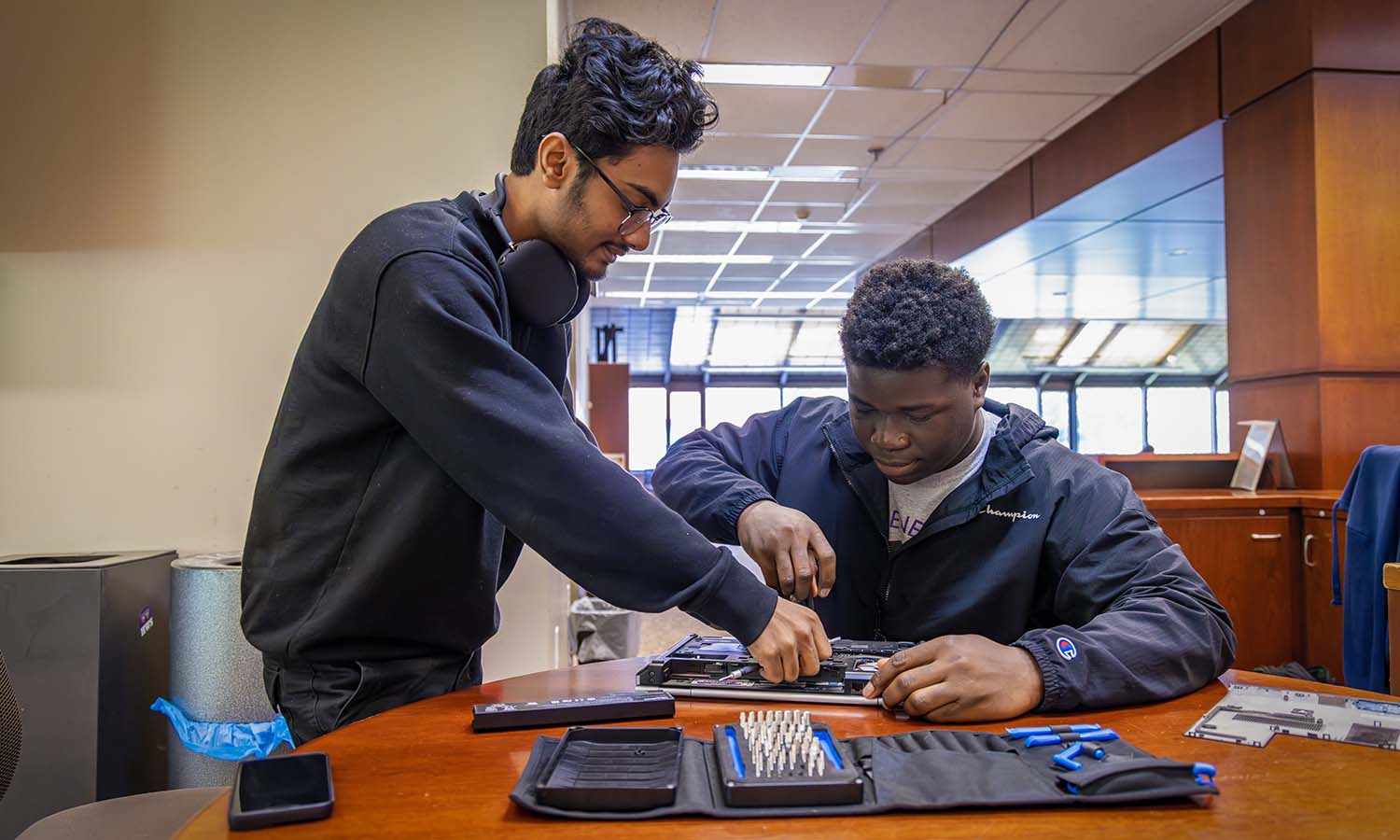 In the Warren Hunting Smith Library, Souvick Rodrigues ’25 and Godson-Kemfon Umoren '25 repair a laptop at the IT Services helpdesk.